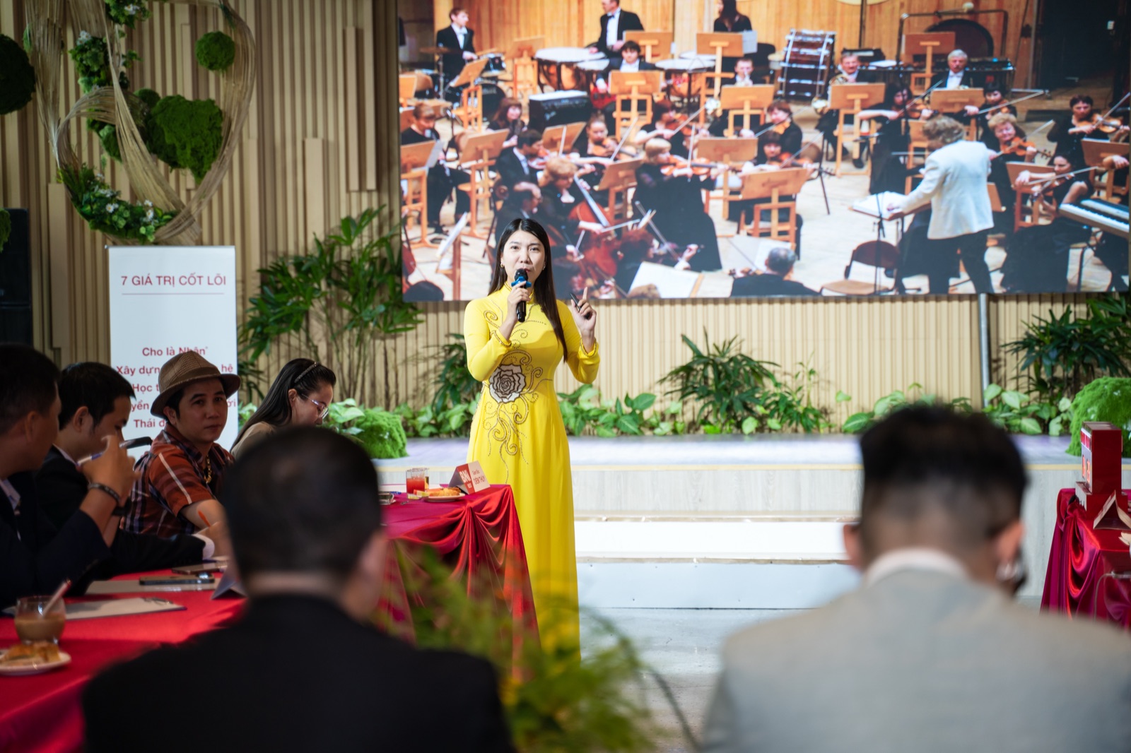Thái Phương Anh nói trước đám đông trong tà áo dài vàng, tay cầm micro